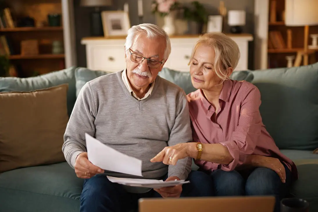 Elderly pair discussing paperwork on couch