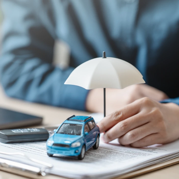 Small blue car beside white umbrella