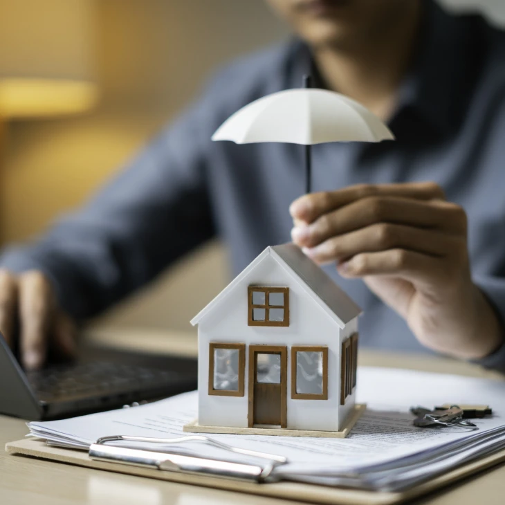 Man holding umbrella over house model