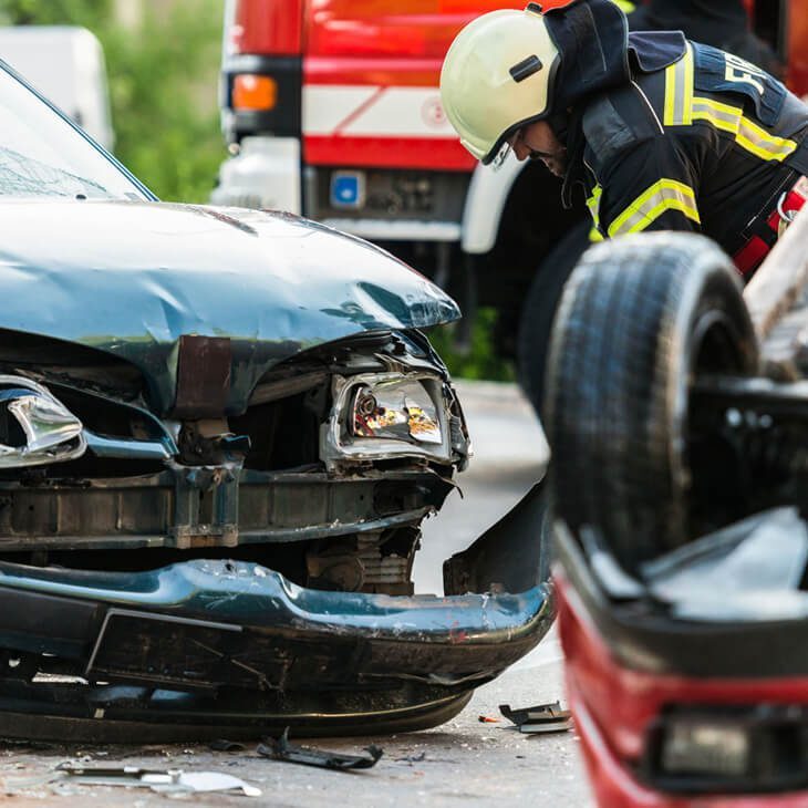 Firefighter inspecting damaged car at accident scene
